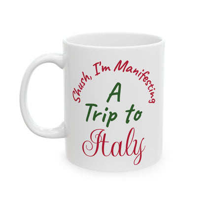 White mug with text 'Shush, I'm Manifesting A Trip to Italy' in red and green on a white background