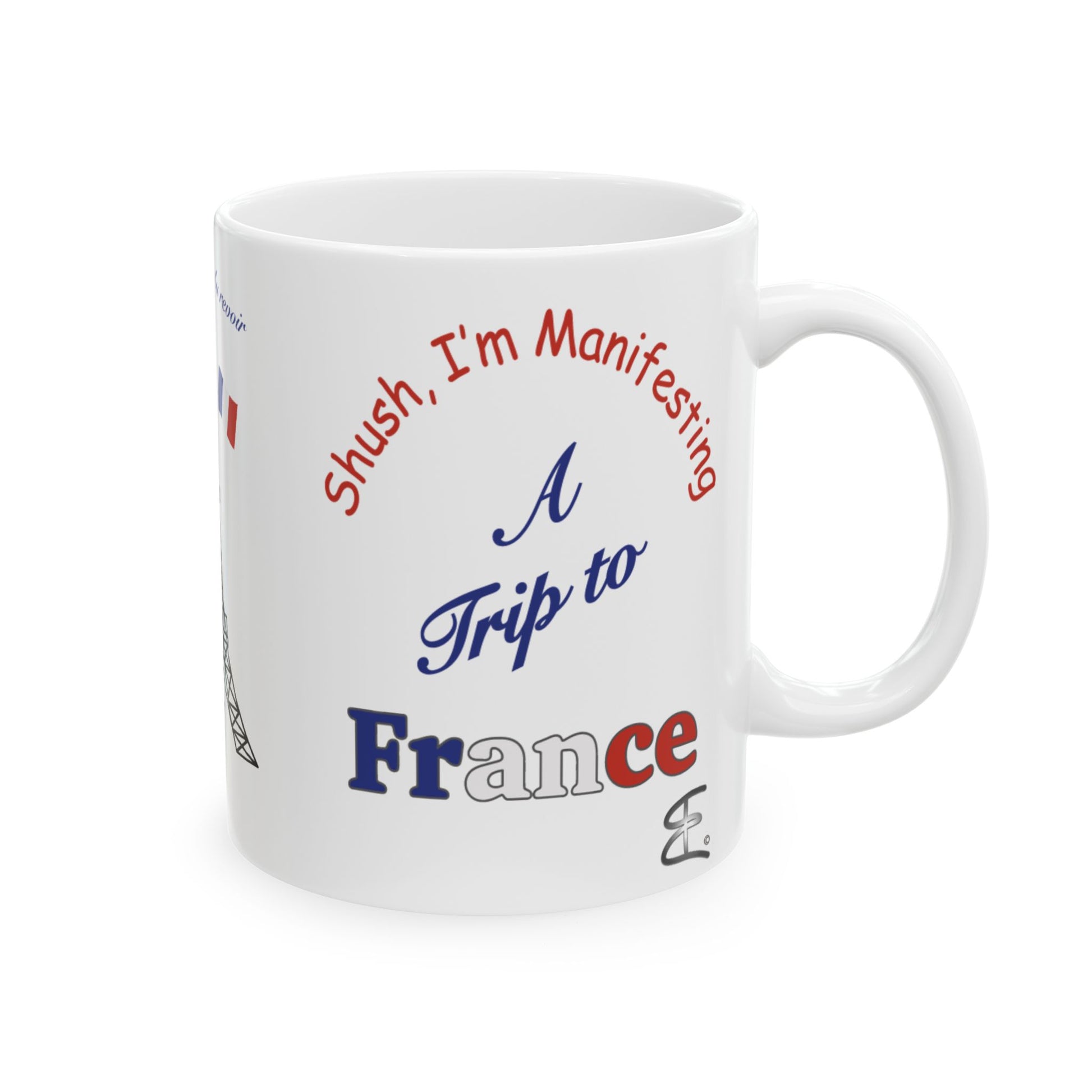 A white ceramic coffee mug with a humorous travel-themed graphic that reads 'Shush, I'm Manifesting A Trip to France' in red, blue, and white lettering.