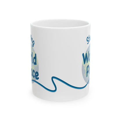 A white 10oz ceramic mug with a blue and light green graphic design featuring the words 'Shush, I'm Manifesting World Peace' on a clean white background.