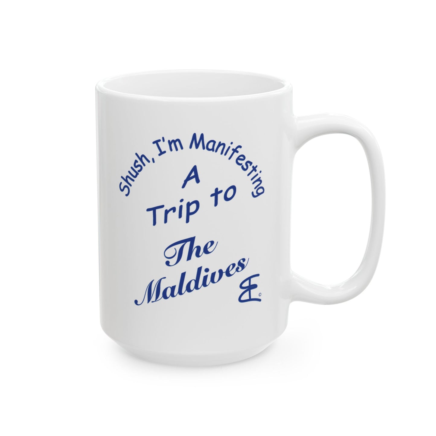 A white ceramic coffee mug with blue printed text that reads 'Shush, I'm Manifesting A Trip to The Maldives'.