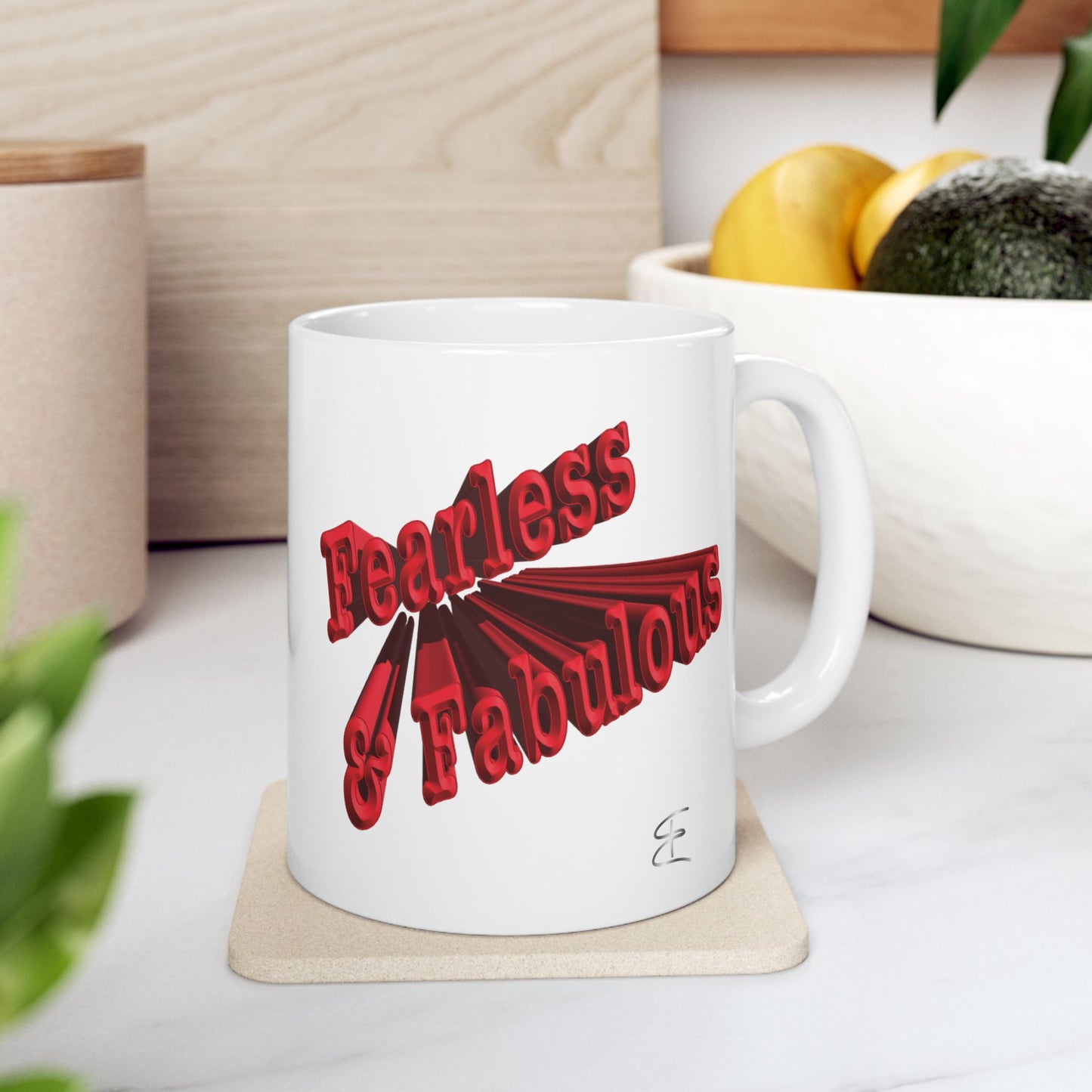 A white ceramic mug with a red graphic text design that reads 'Fearless &  Fabulous' sitting on coaster.