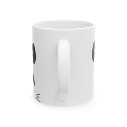 A white ceramic mug with a black circular graphic and partial black text, shown from a side angle on a white background.