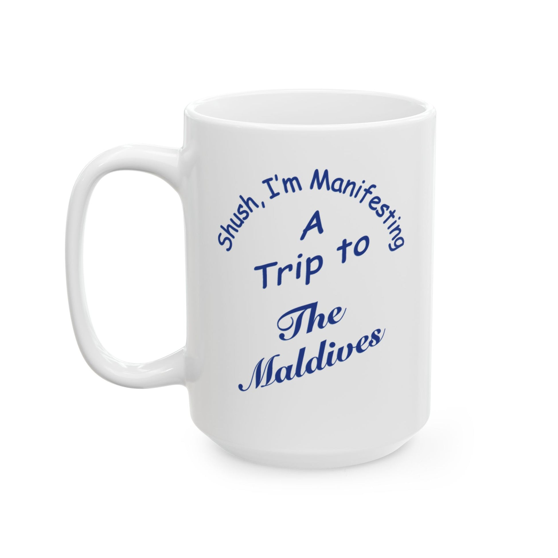 A white ceramic coffee mug with a blue printed text design that reads 'Shush, I'm Manifesting A Trip to The Maldives' on a clean white background.
