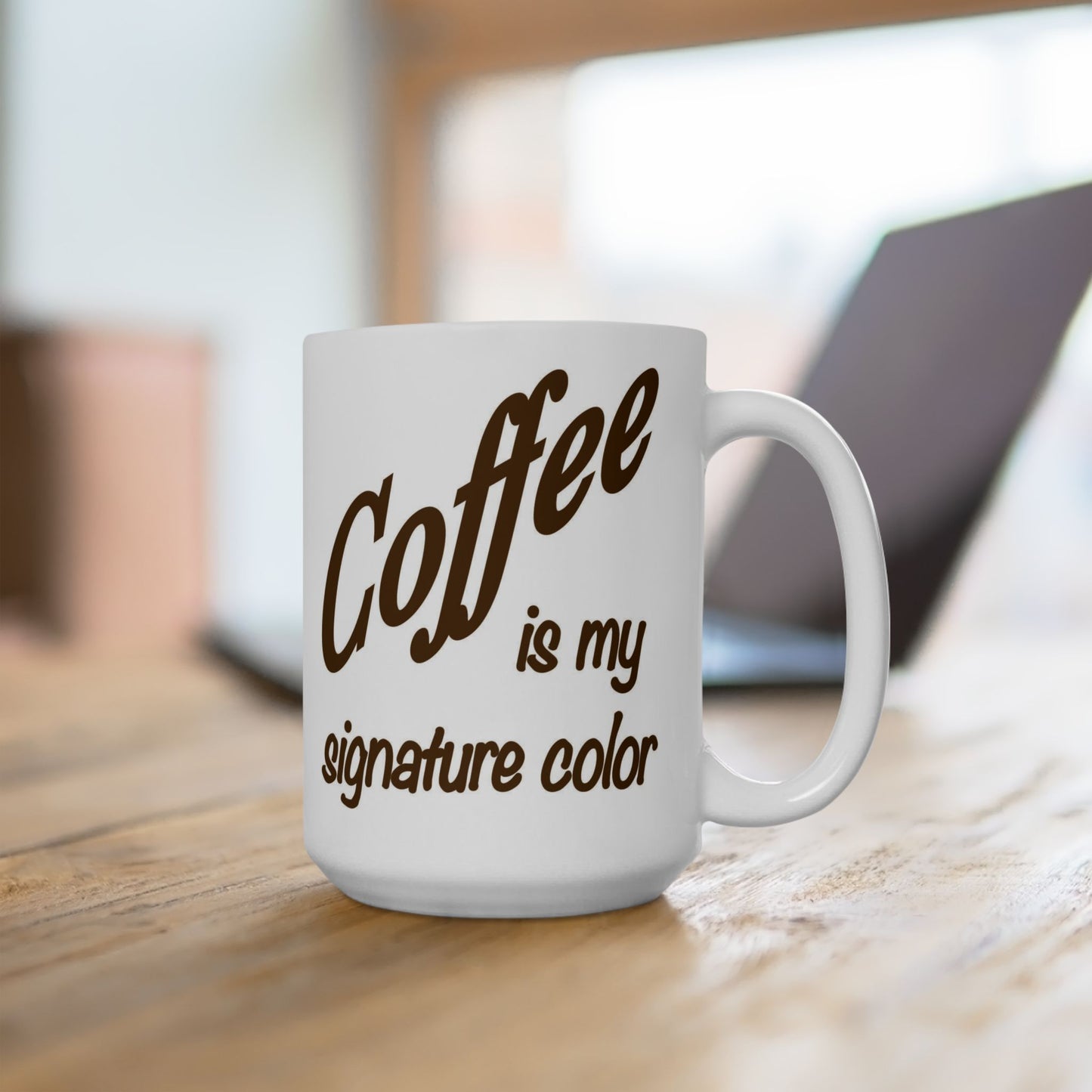 White mug with 'Coffee is my signature color' text on a wooden surface.
