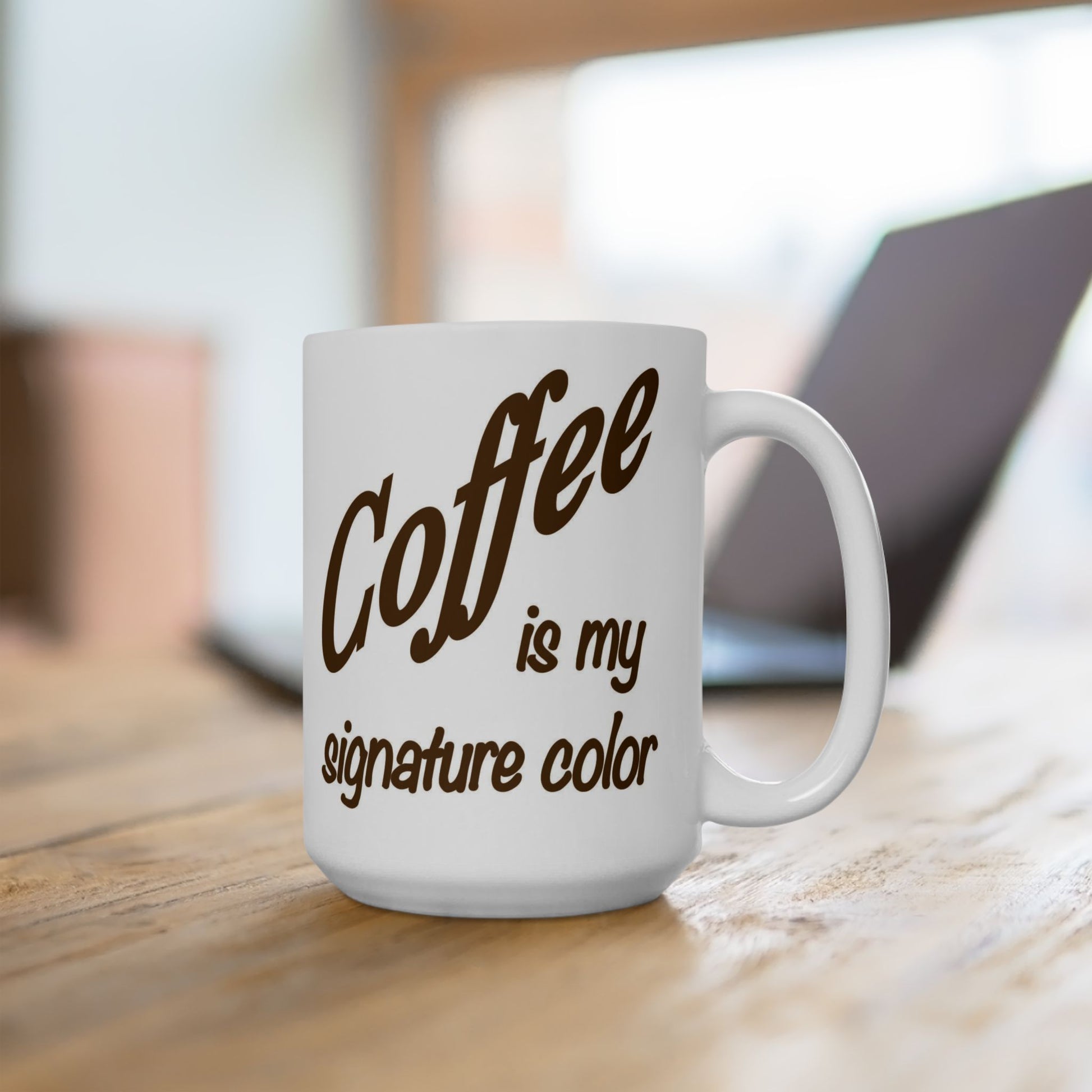 White mug with 'Coffee is my signature color' text on a wooden surface.