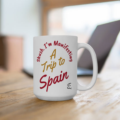 'Shush I'm Manifesting A Trip to Spain' 15oz ceramic mug lifestyle picture on wooden desk with laptop in background.