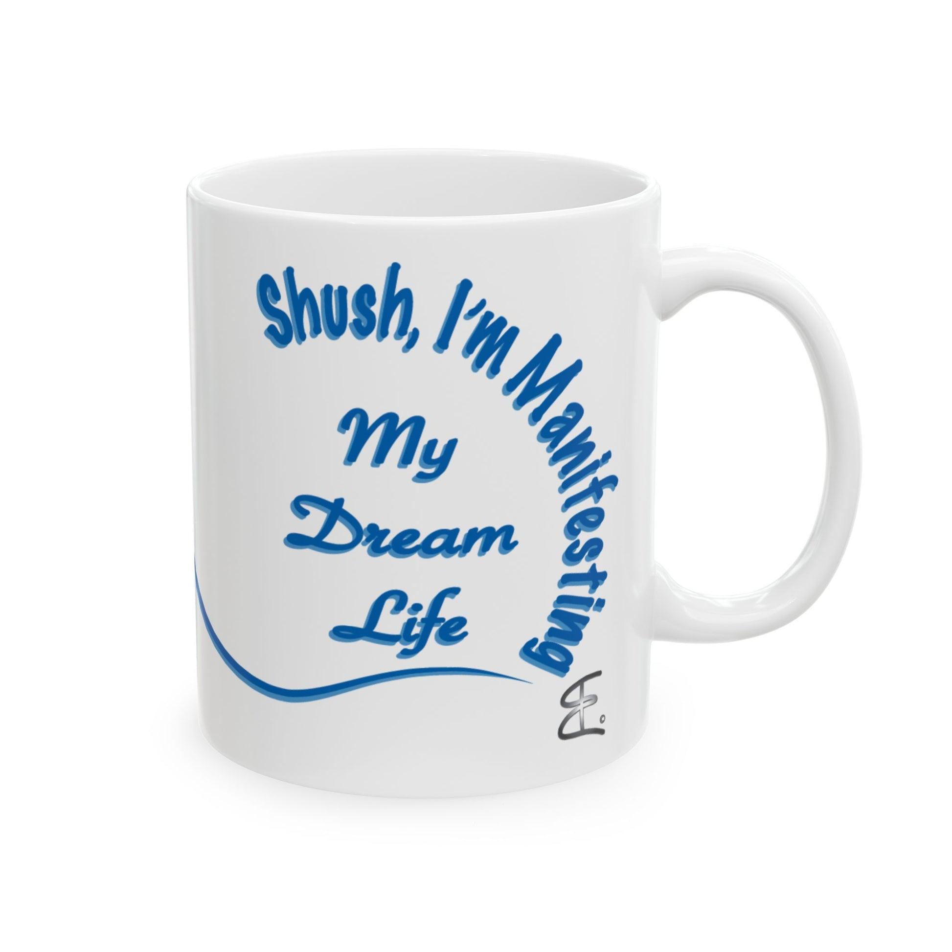 A white ceramic mug with blue text reading 'Shush, I'm Manifesting My Dream Life' and a blue curved line, shown on a plain white background.