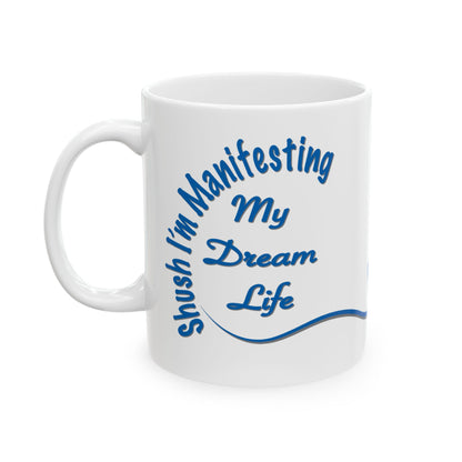 White ceramic mug with the text 'Shush, I'm Manifesting My Dream Life'

