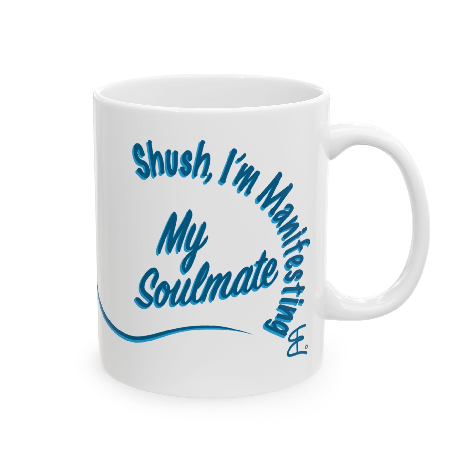 A white ceramic coffee mug with blue text that reads 'Shush, I'm Manifesting My Soulmate' in a stylized script, shown on a plain white background.