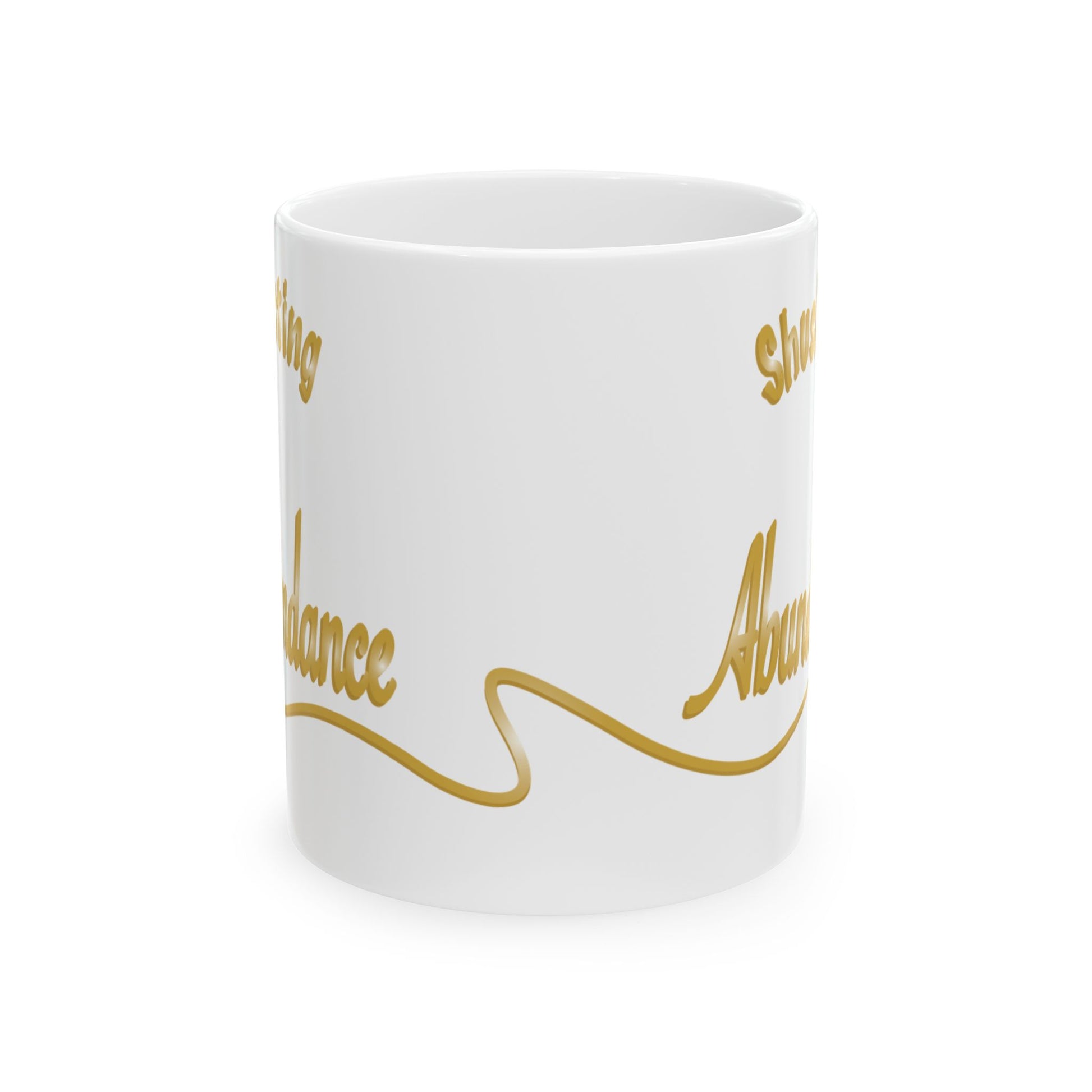 A white ceramic mug with elegant gold cursive text the word 'Abundance' is partially visible with a flowing gold line, shown on a clean white background.