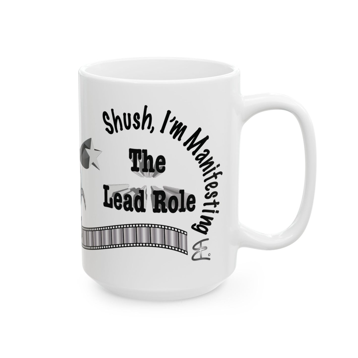 A white ceramic mug with a black printed graphic that reads 'Shush, I'm Manifesting The Lead Role' with a filmstrip design, shown on a plain white background.
