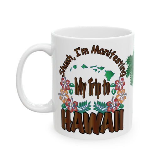 A white ceramic mug with a colorful graphic design featuring the text 'Shush, I'm Manifesting My Trip to HAWAII' in brown and green, surrounded by tropical flowers and palm leaves.