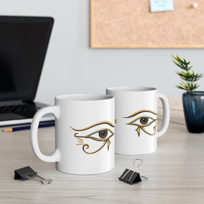 Two white mugs showing the eye of Horus is on both sides of the mug, on a desk with office items.