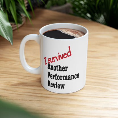 "I Survived Another Performance Review" mug displayed on plain background, relatable corporate sarcasm coffee cup for desks and home office

